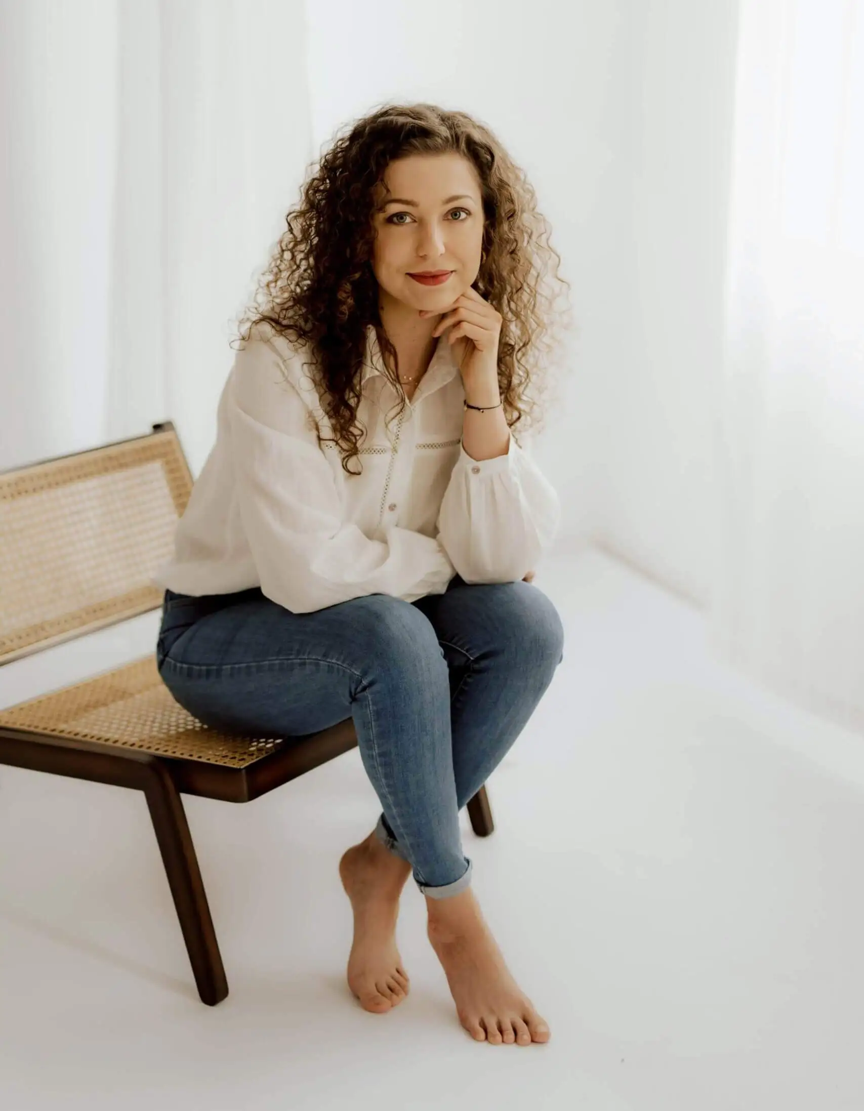 Kobieta w eleganckiej białej koszuli i dżinsach, uśmiechająca się profesjonalnie do obiektywu, symbolizująca wiedzę i doświadczenie w optymalizacji procesów obsługi klienta.